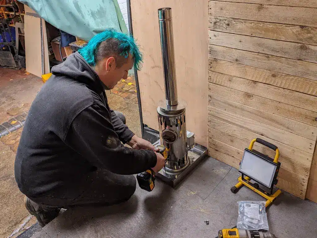 Marine Heating Solutions engineer installing a stainless steel diesel stove during a professional van conversion project.