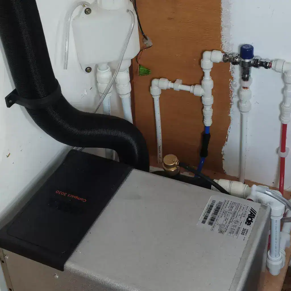 A professional installation of an Alde Compact 3030 LPG combi boiler showing plumbing connections and flue ducting.