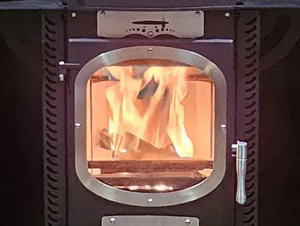 A close-up of the Go Eco Adventurer 5 boat stove showing a clear view of the fire through the large air-washed glass window.