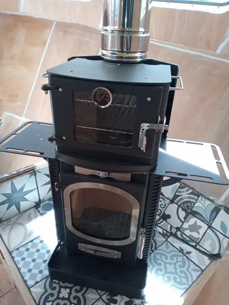 A Go Eco Adventurer 5 boat stove featuring the optional top-mounted oven, stainless steel side warming plates, and a twin-wall flue installation.
