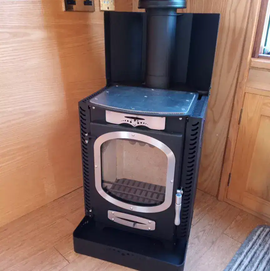 A Go Eco Adventurer 5 stove installed with a specialized marine hearth and rear heat shield, showing the reduced safety clearances required for boat cabins.