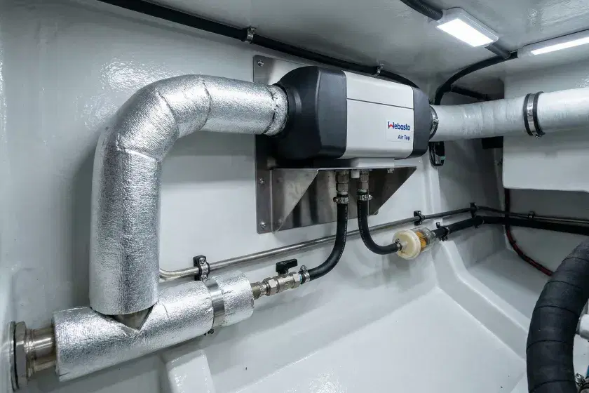 A diesel heater unit professionally mounted in a boat's technical locker with high-temperature exhaust lagging and marine-grade ducting.