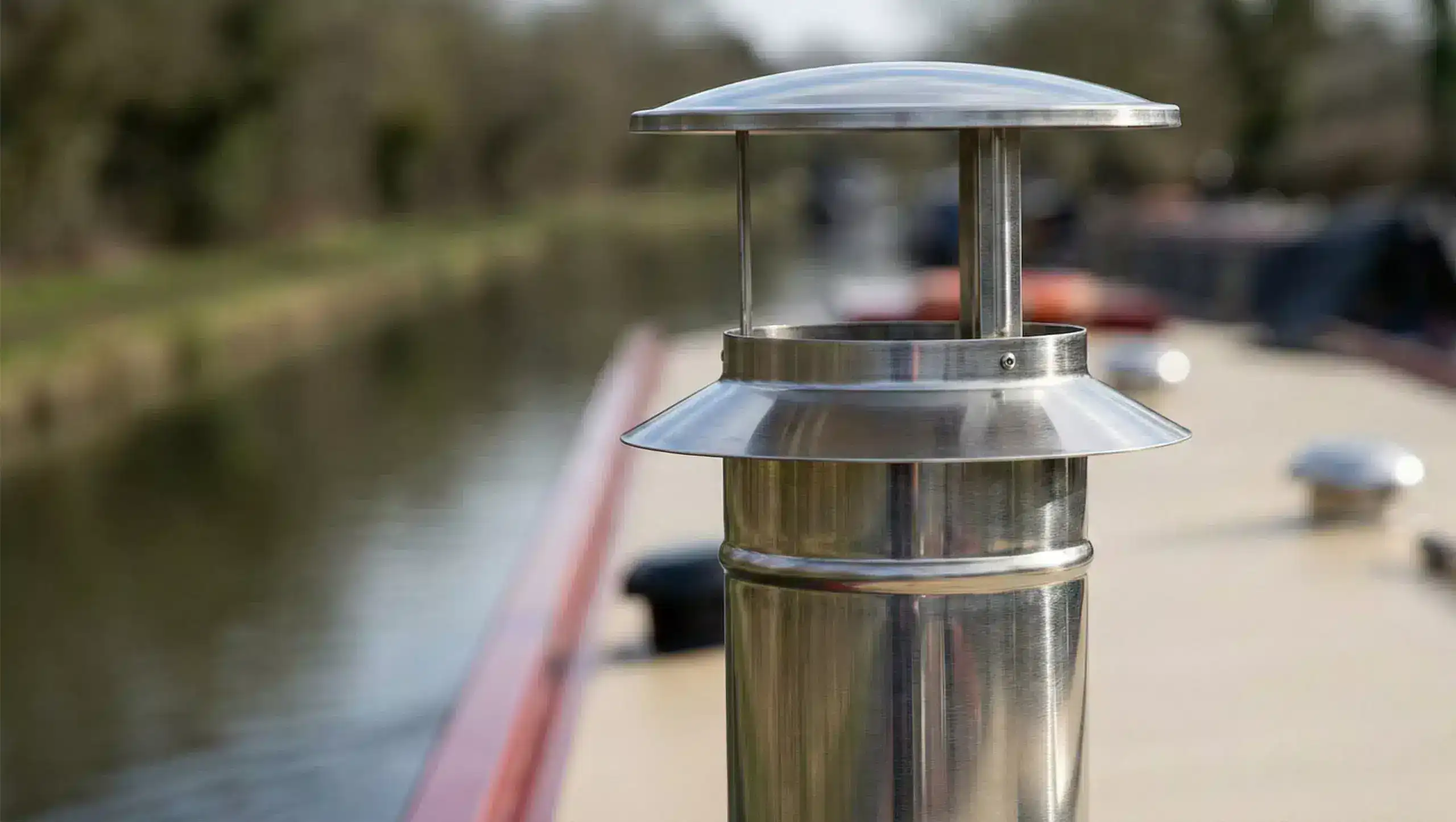 Close-up technical view of a stainless steel twin-wall insulated flue system connecting to a boat stove, highlighting the safety clearance.