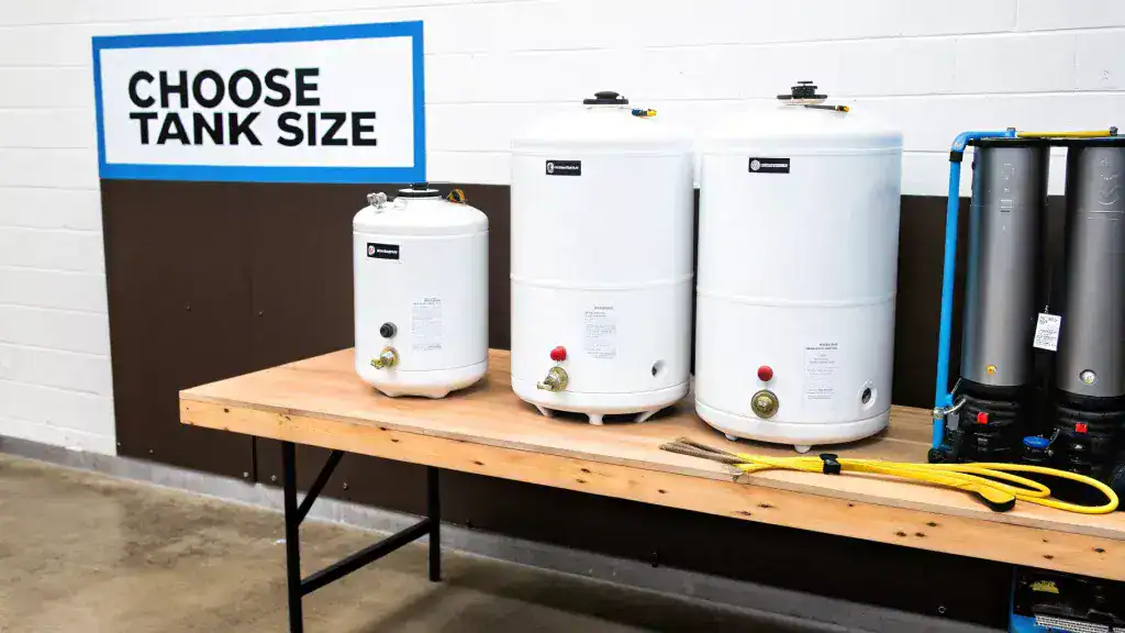 Multiple white tank water heaters of various sizes displayed on a wooden table for selection.