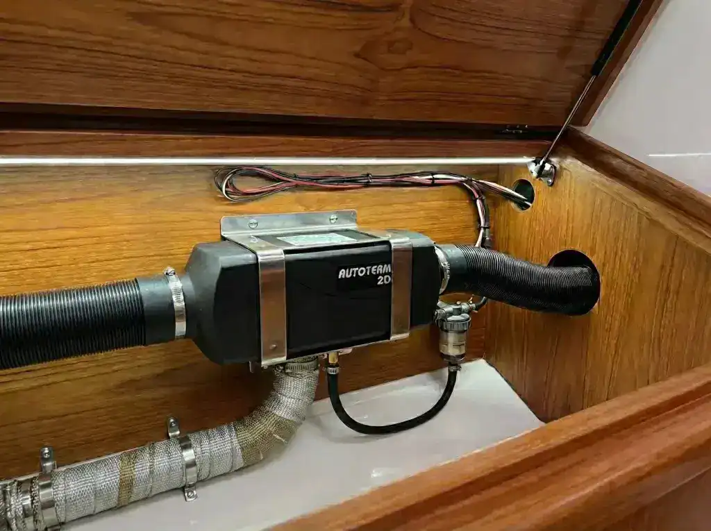 Autoterm 2D diesel heater installed in a wood-lined boat locker with air ducting, fuel filter, and professional wiring.
