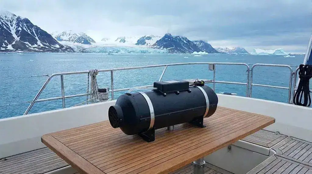 An Autoterm 9D 8kW diesel heater positioned on the rear deck of a large yacht sailing through icebergs in the Arctic Circle.