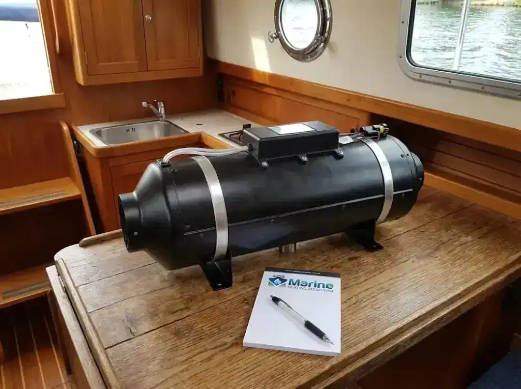 The industrial-grade Autoterm 9D diesel heater unit on a boat cabin table next to a Marine Heating Solutions notepad.
