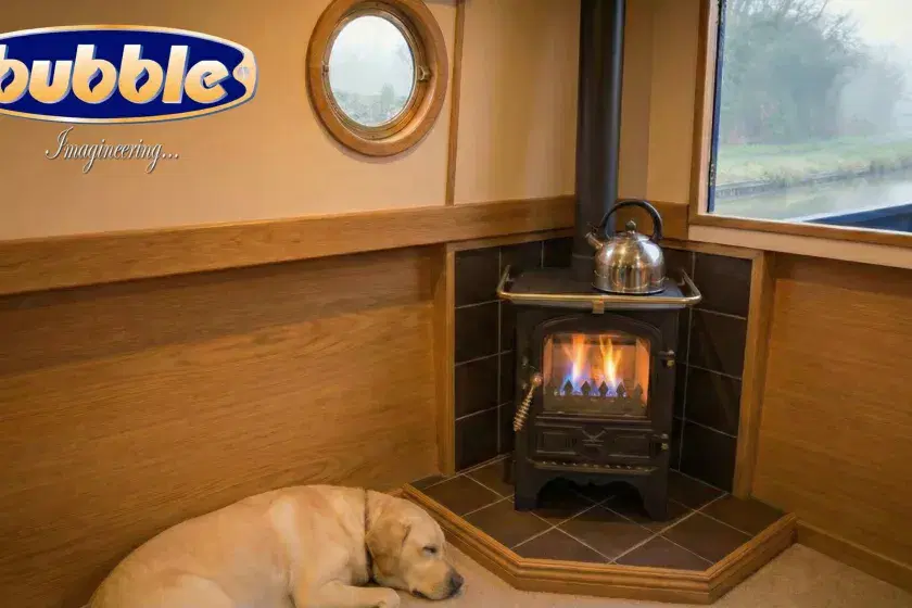 A Bubble diesel boat stove installed in a narrowboat cabin with a blue flame visible, featuring a Labrador dog sleeping nearby on a wooden floor.