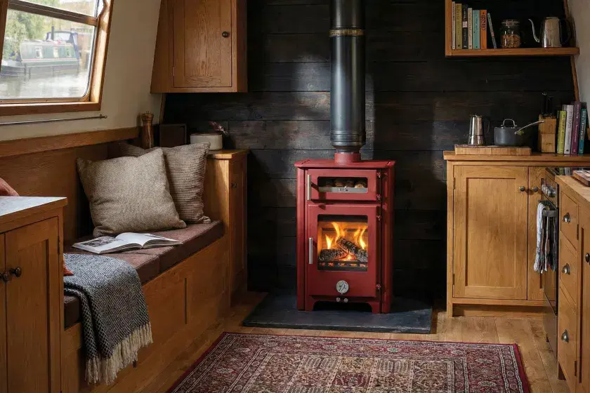 Professional installation of a red Chilli Penguin Fat Penguin stove in a narrowboat cabin, featuring a BS 8511 compliant twin-wall insulated flue and starter pipe by Marine Heating Solutions.