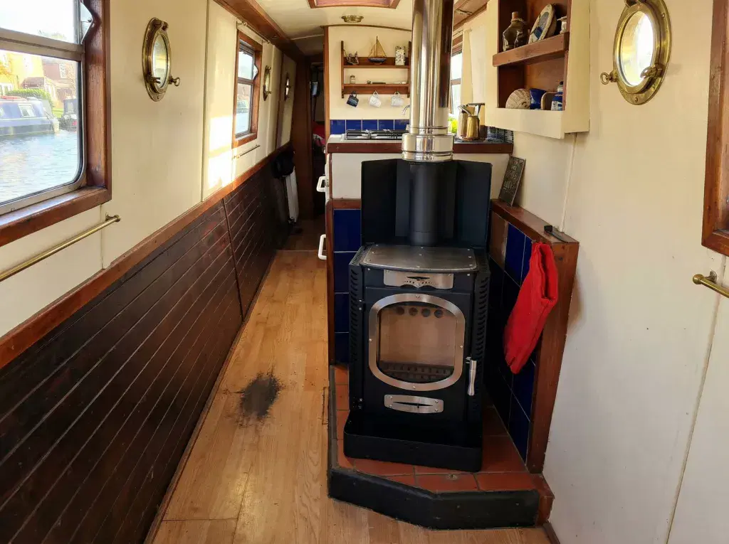 Professional installation of a Go Eco Adventurer 5 multi-fuel stove in a narrowboat interior, featuring a BS 8511 compliant marine hearth and integrated heat shield.