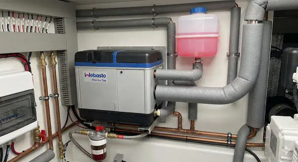 A professional BSS compliant marine diesel boiler installation featuring an expansion tank, lagged coolant pipework, and a bronze fuel shut-off valve.