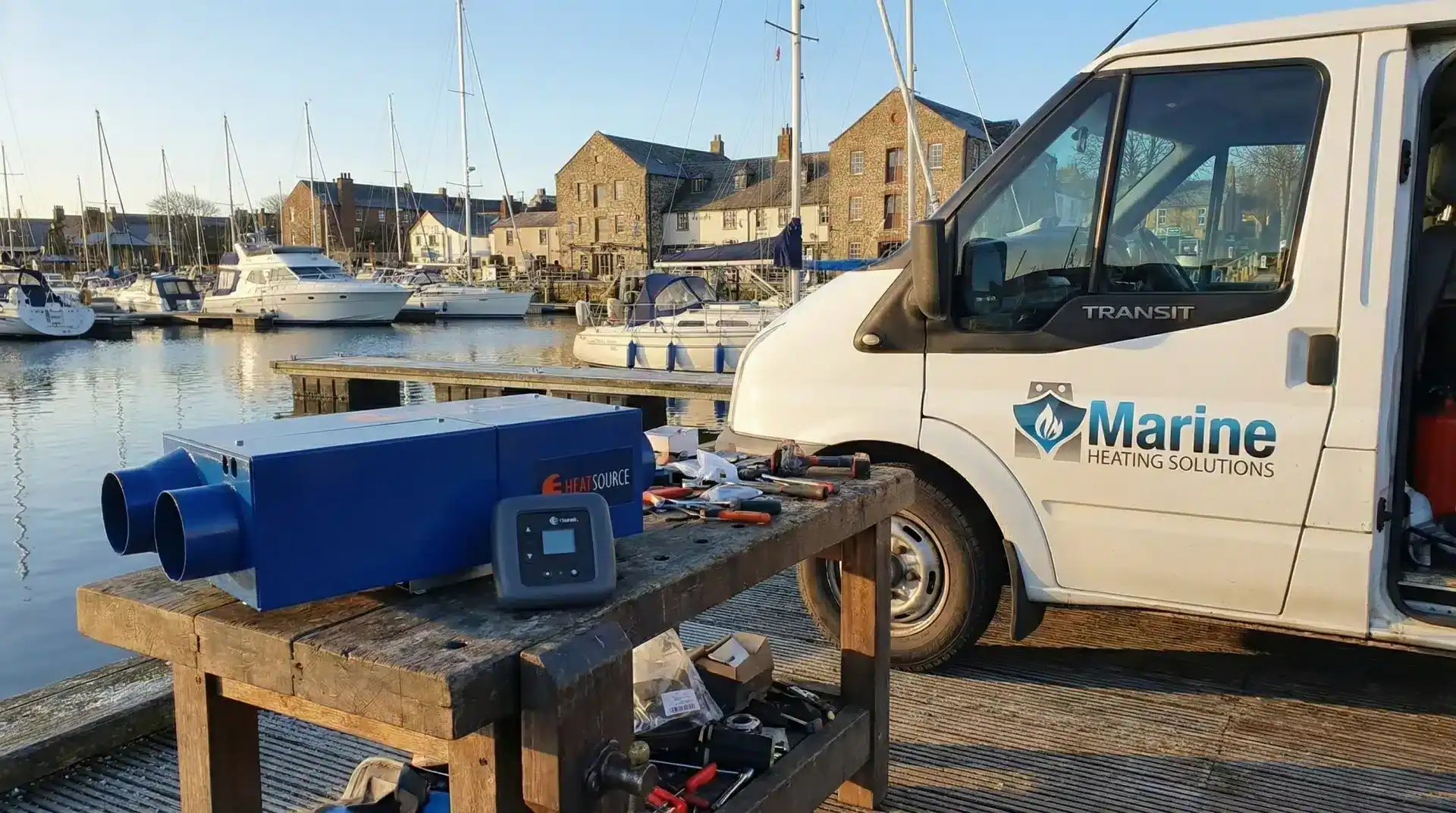 Propex HS2000 LPG marine heater on a workbench next to a Marine Heating Solutions service van at a marina.