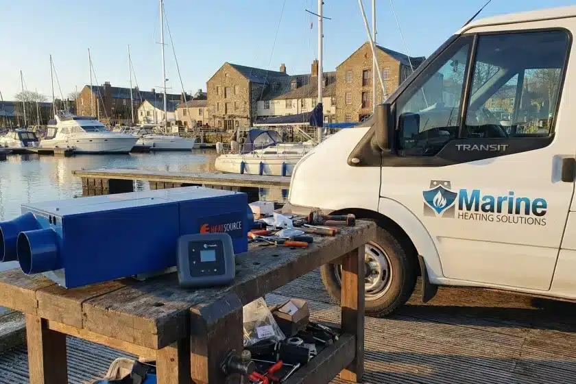 Propex HS2000 LPG marine heater on a workbench next to a Marine Heating Solutions service van at a marina.