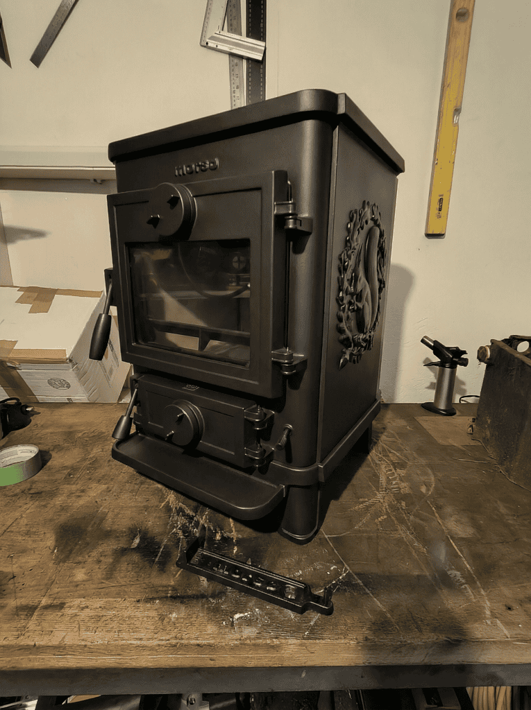 A refurbished Morso Squirrel 1412 Stove, sittting on a workbench, showing front and right hand side panel with squirrel motif.