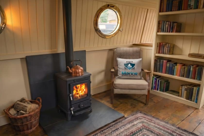 A professionally installed Salamander Hobbit multi-fuel stove burning brightly in a cozy, wood-paneled narrowboat cabin, featuring a Marine Heating Solutions service toolbox.