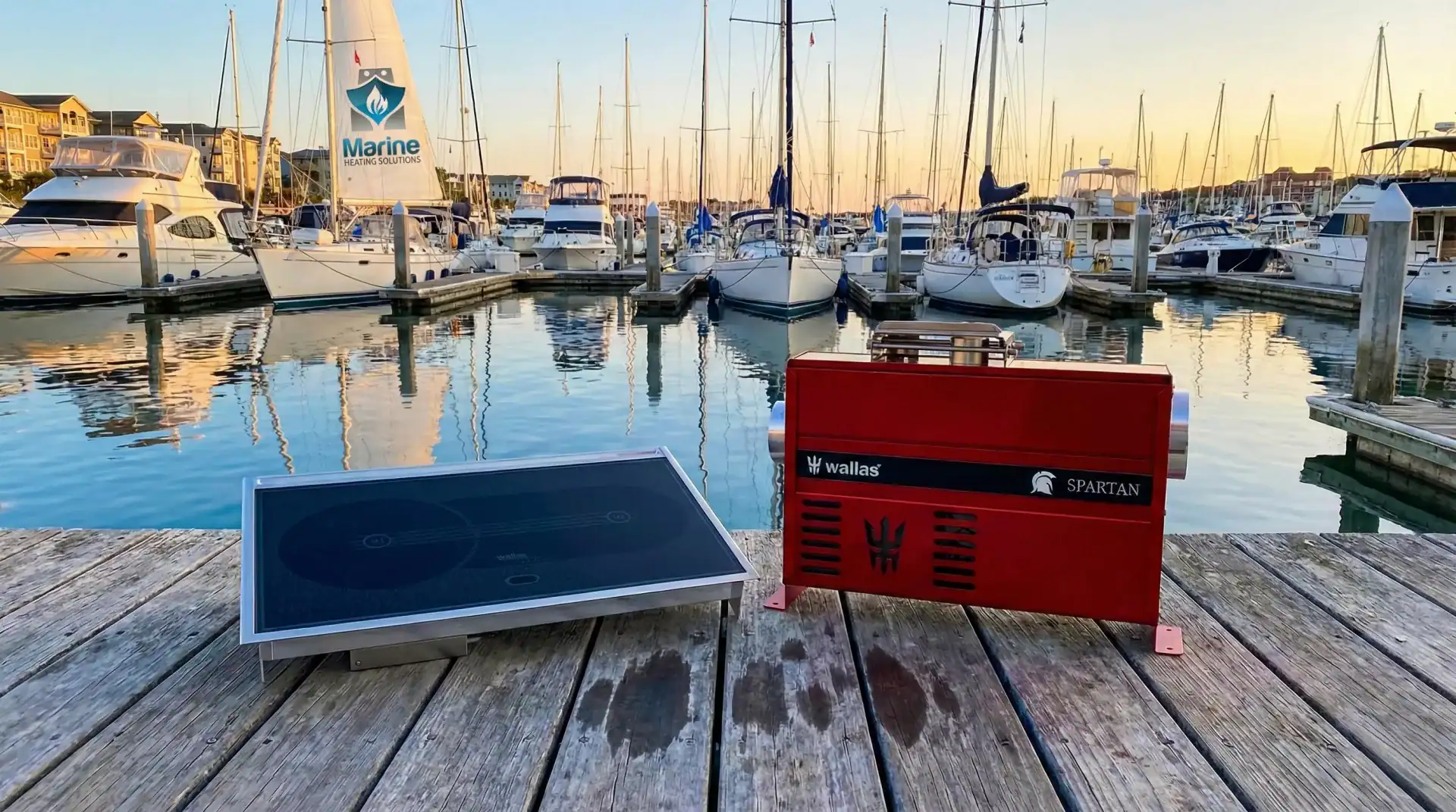 Wallas 85DT diesel hob and Wallas Spartan air heater displayed on a wooden dock with sailboats in the background marina.