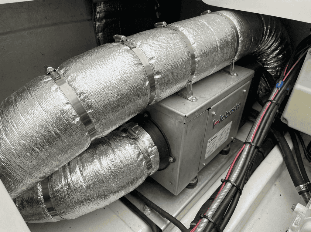 Close-up of high-quality marine-grade insulation and ducting connected to a Webasto heater unit showing professional stainless steel clipping and secure mounting.