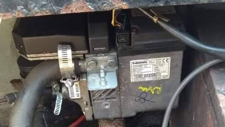 A close-up shot of a Webasto Thermo Top C marine diesel heater installed in a boat, showing the manufacturer's identification plate and hose connections.