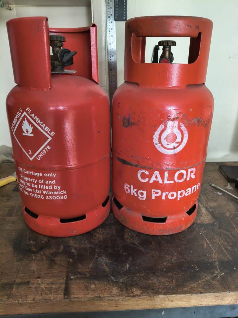 Pair of red Calor 6kg propane gas cylinders on workbench